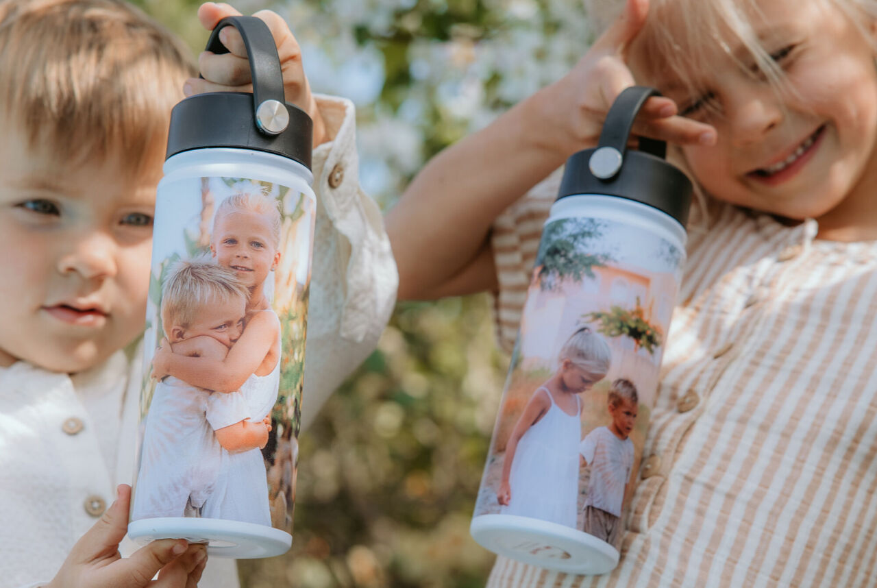 Deux enfants souriants tenant leurs gourdes personnalisées à portraits